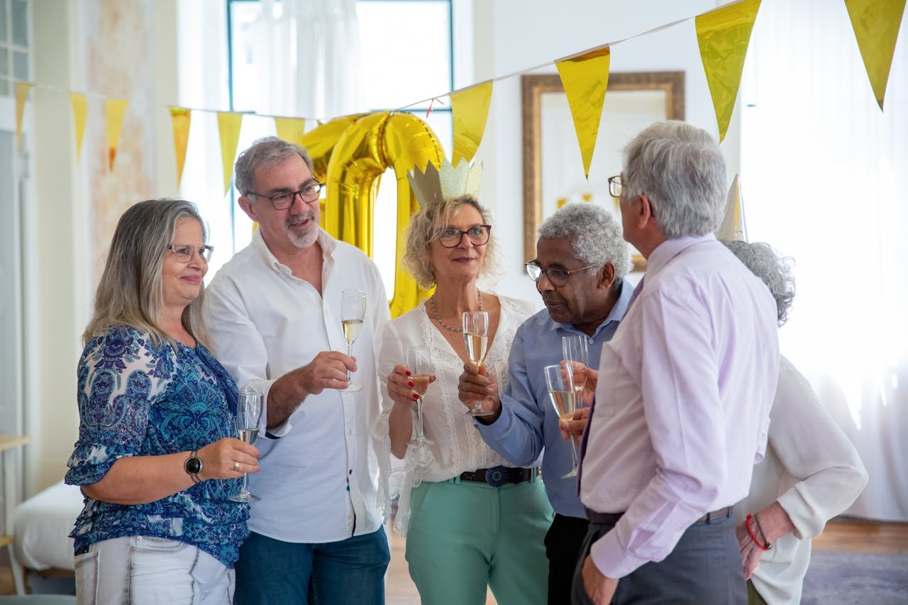 A joyful gathering of senior friends celebrating with champagne indoors, featuring smiles and festive decor.